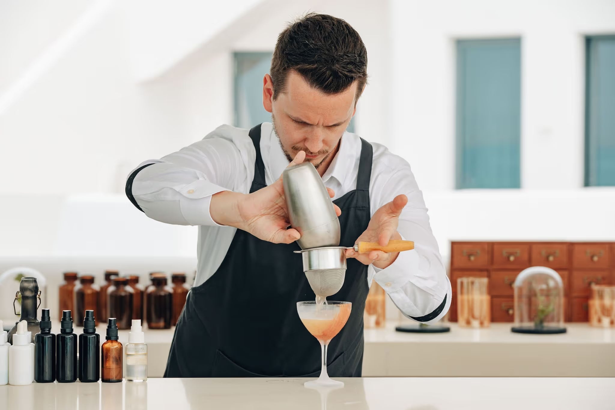 A man in an apron is making a drink